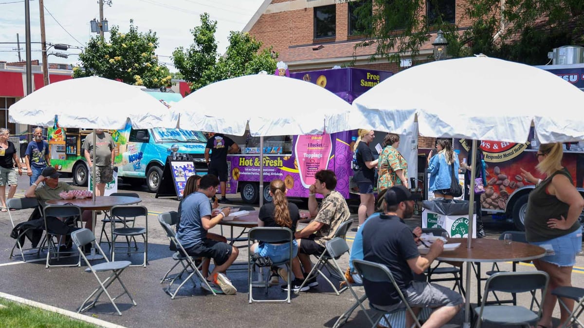 Families at outdoor tables in Grove City Town Center during a community festival