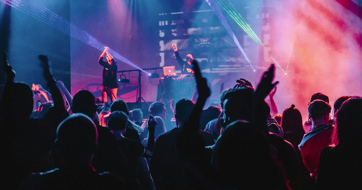 Synthwave concert lights over an outdoor pavilion crowd