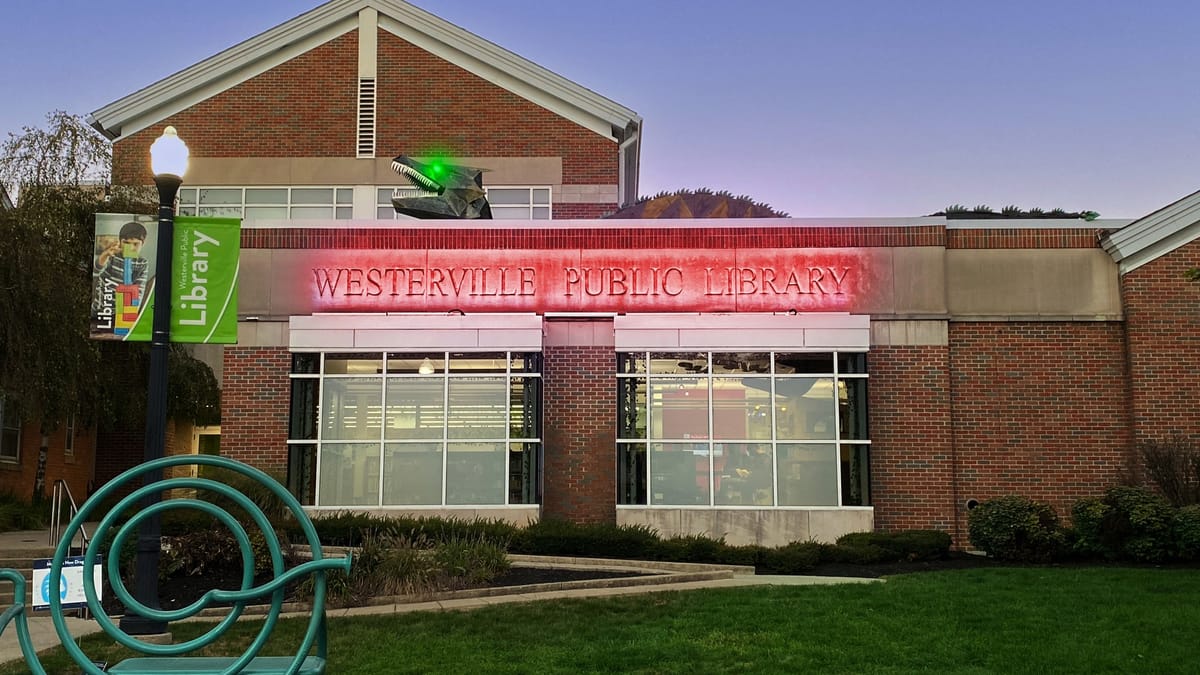 Westerville Public Library at dusk with festive rooftop creature for Wizards and Wands