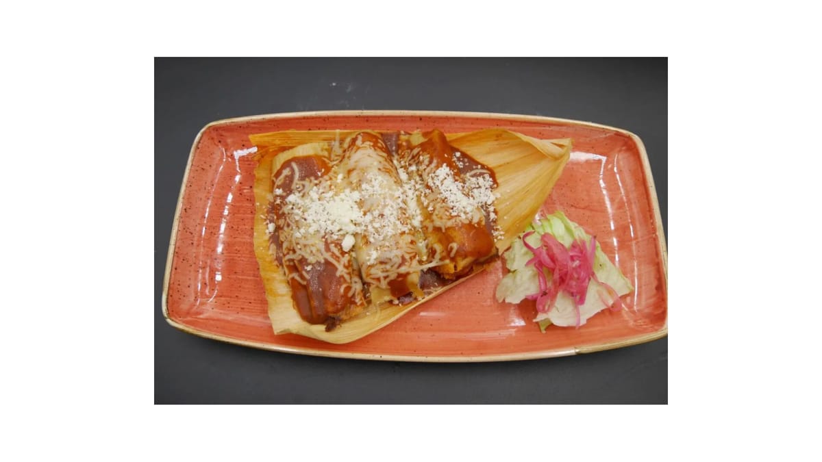 Tamales with red sauce and cheese on a terracotta plate at Braseros Bar and Grill