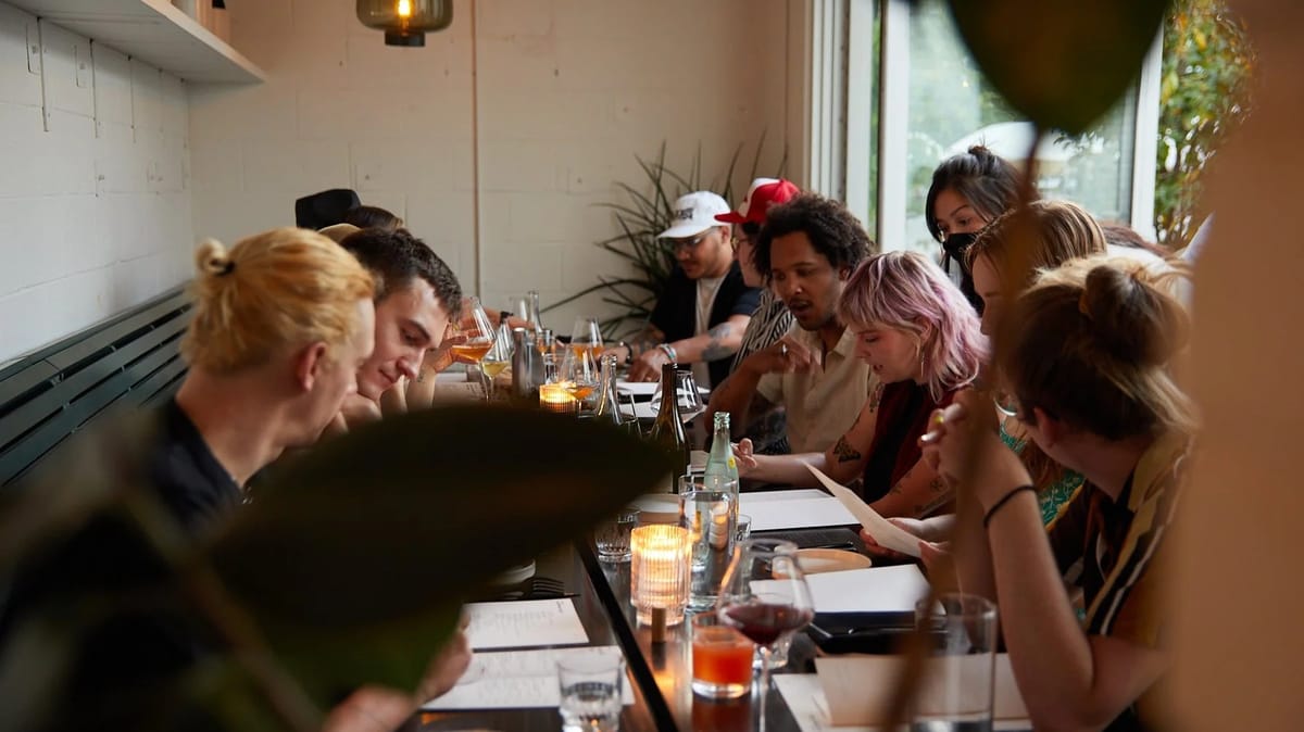 Communal candlelit dining table with wine glasses inside Comune on Parsons Avenue