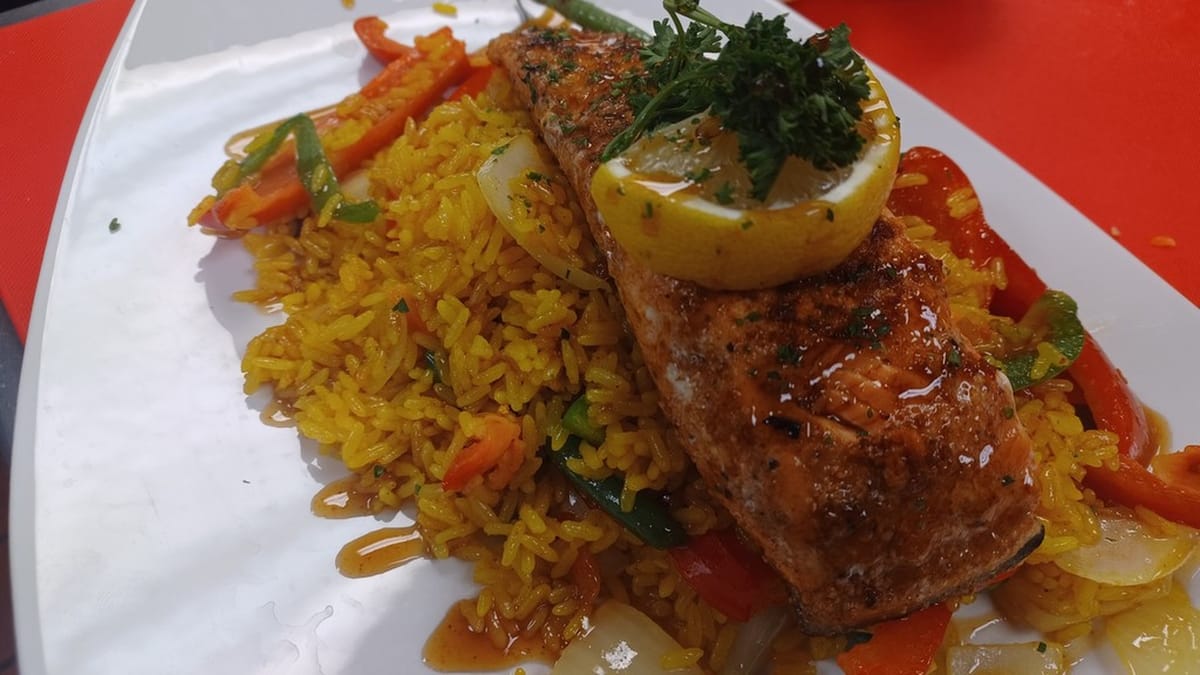Plated glazed salmon with lemon, parsley, yellow rice, and peppers from Fountains Take 2
