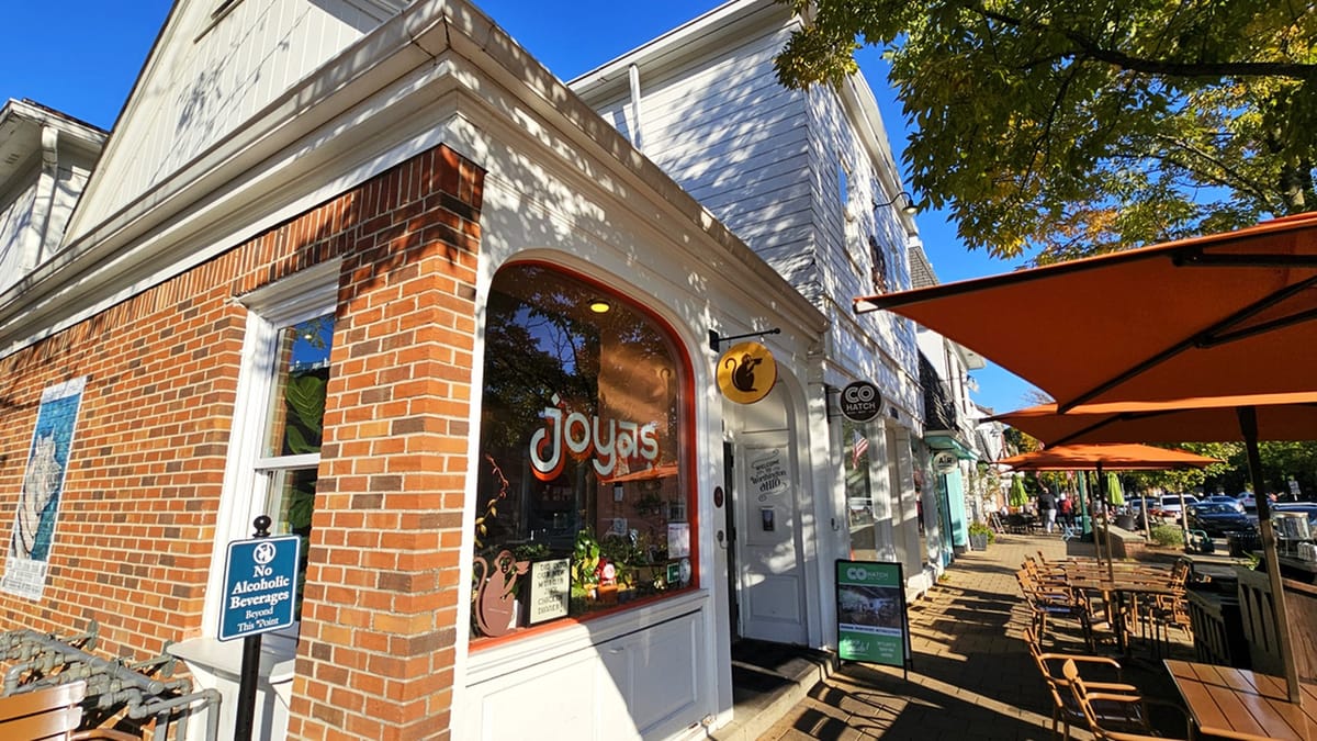 Joya's Worthington storefront with orange joyas window lettering, monkey logo sign, and sidewalk patio umbrellas