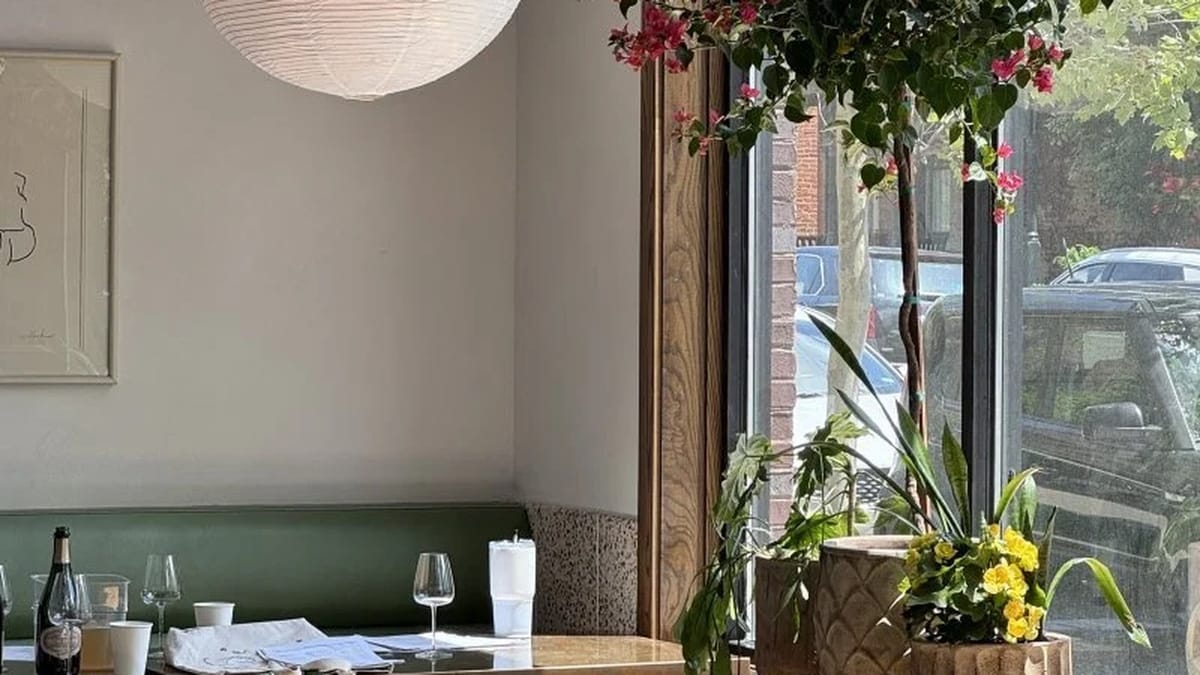 Bright Metsi's Short North dining corner with sage banquette, paper lantern, and street window light