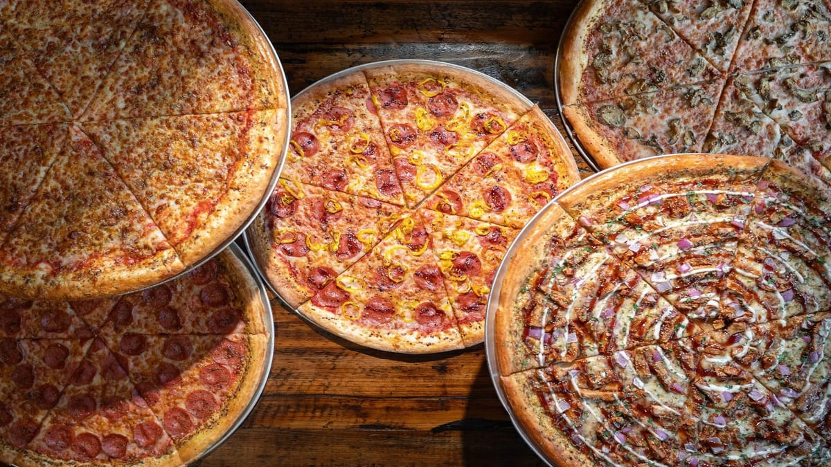 Assorted Mikey's Late Night Slice pizzas on metal trays