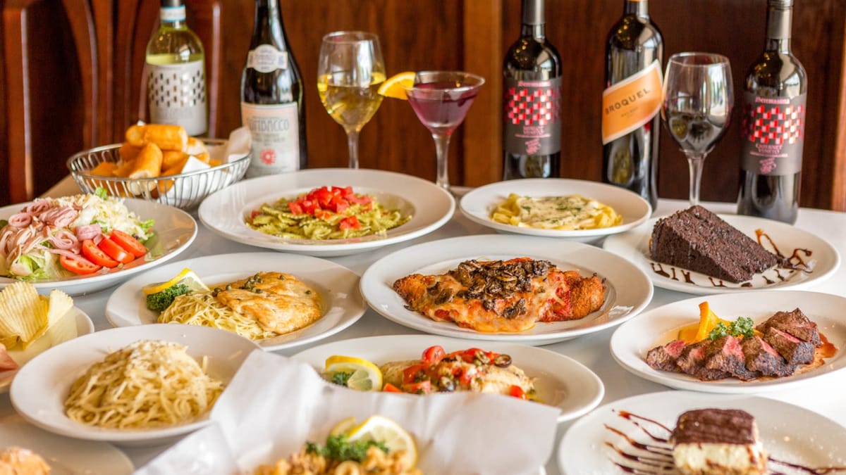 Family-style Italian feast spread on a white tablecloth inside Milano's restaurant