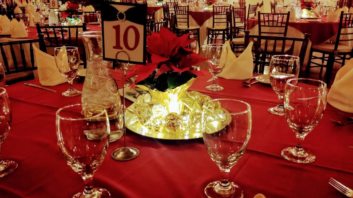 Holiday banquet tables with red linens and poinsettia centerpieces inside Mozart's Bakery and Piano Cafe