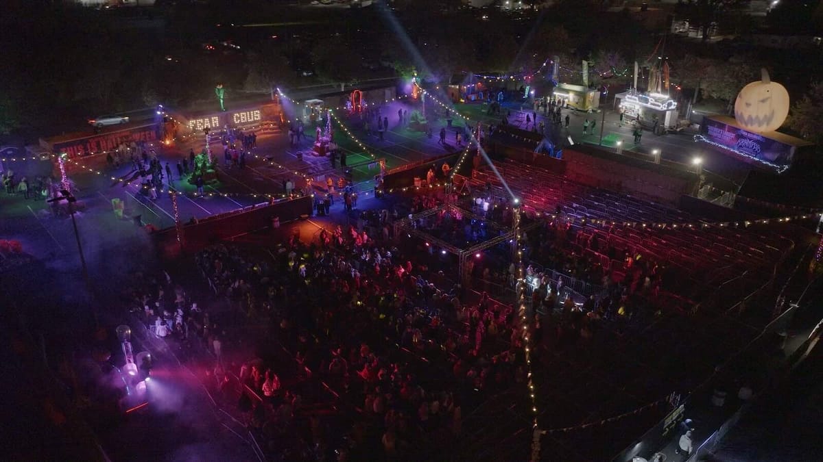 Aerial night view of the Fear Columbus midway lit in purple and red with crowds outside the haunt building