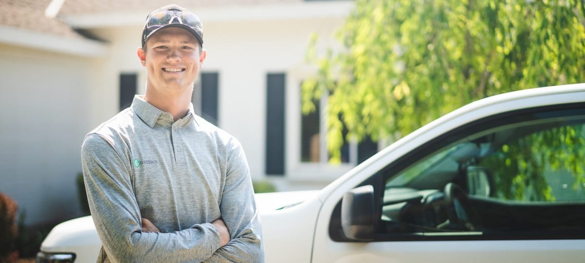 Greenix Pest Control technician in uniform beside a service vehicle