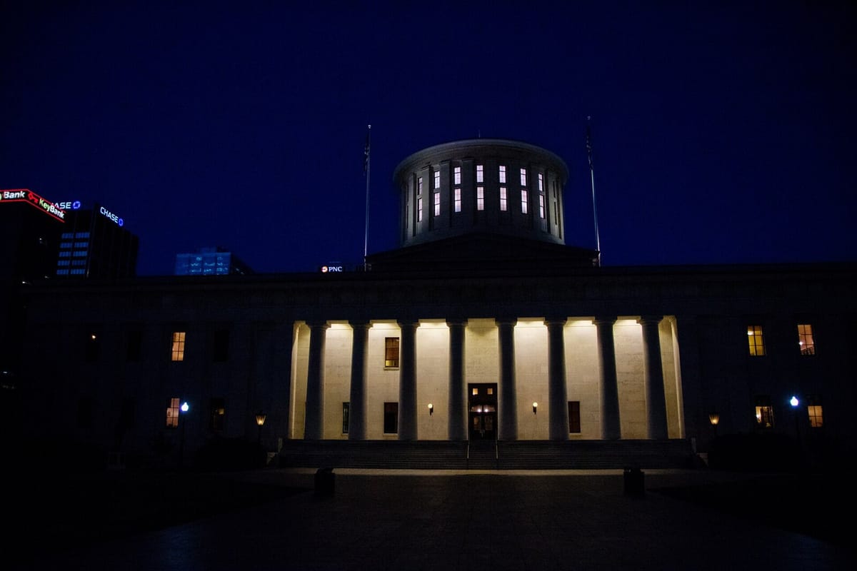 Ohio Statehouse west colonnade and cupola lit up against a dark blue night sky