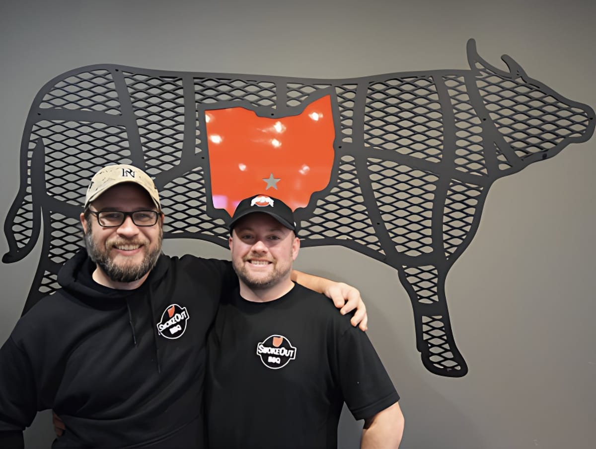 Smoke Out BBQ owners beside Ohio cow art