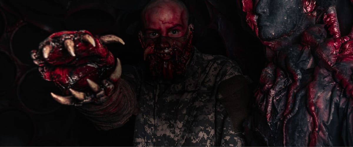 Blood-smeared creature actors reaching toward the camera in dim red light at The Haunt Columbus