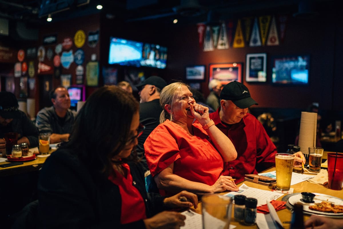 Trivia players laughing over answer sheets at a Columbus pub night