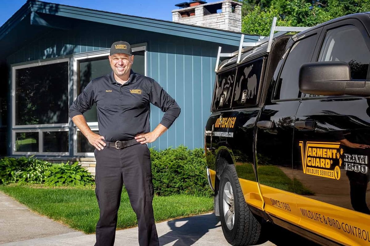 Varment Guard technician standing beside a branded wildlife service truck